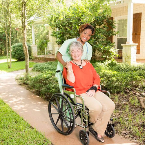 Caregiver assisting elderly woman in wheelchair